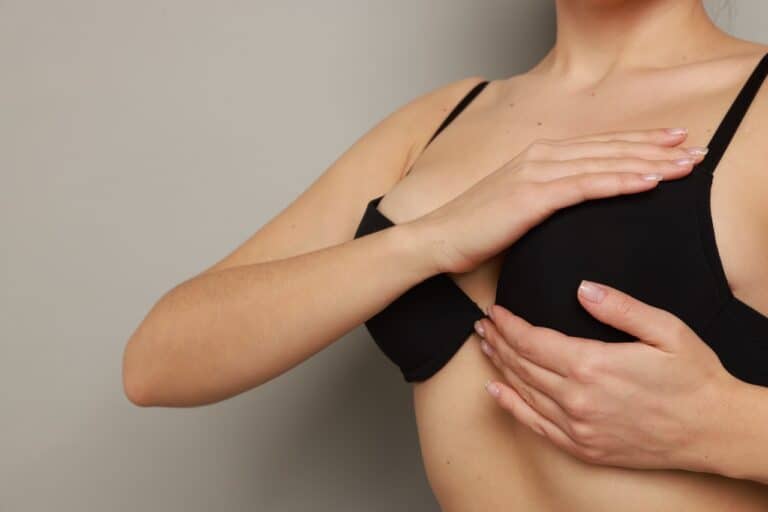 woman in black bra feeling her breast